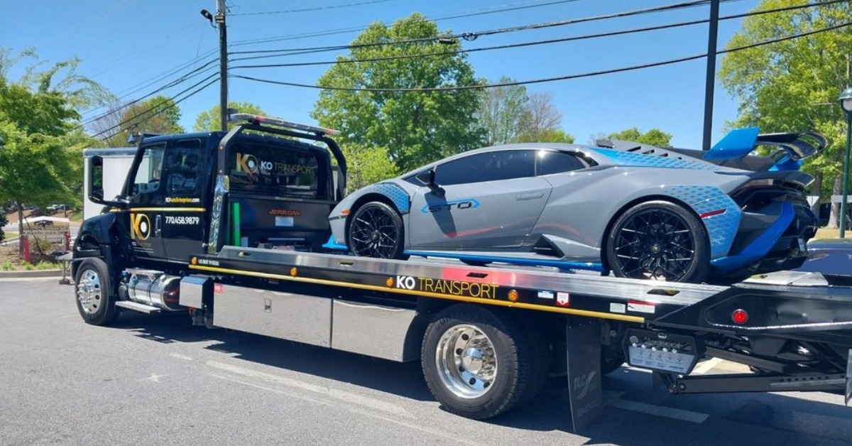 A blue sports car being towed by a tow truck on a city street.